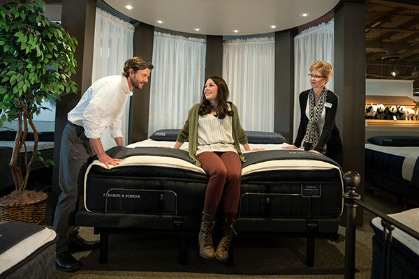 salesperson helping couple with selecting a mattress